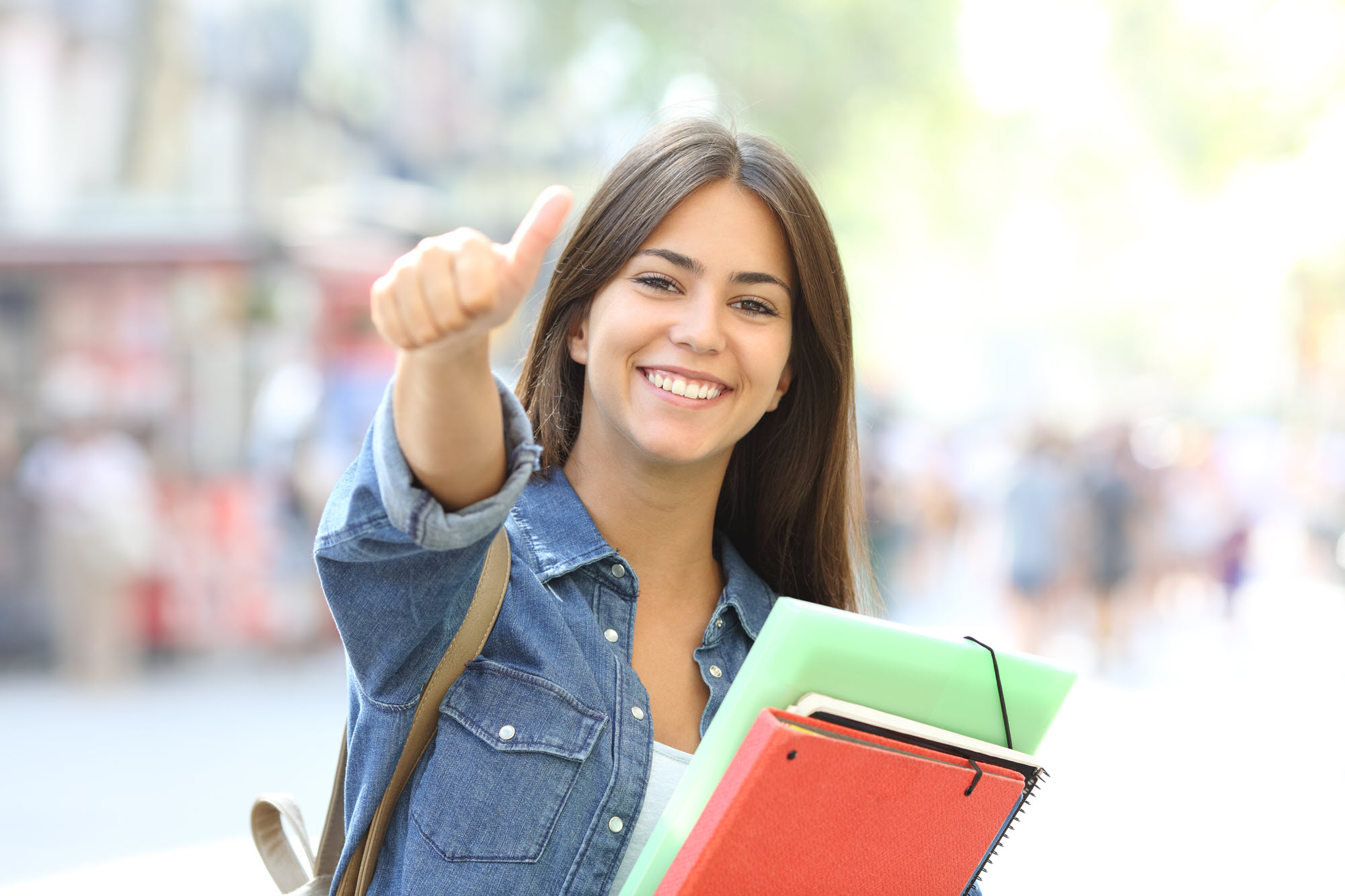 high school girl holding books giving a thumbs up