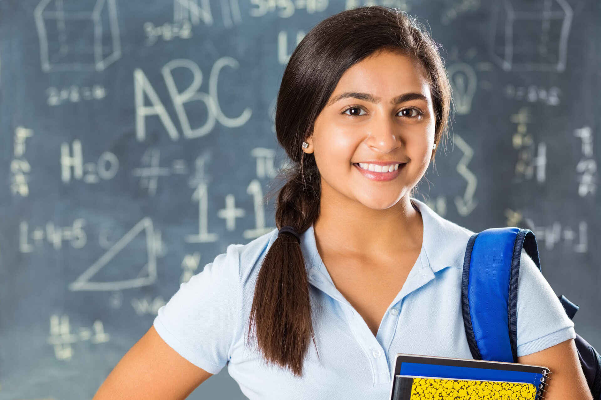 middle school girl smiling in front of a chalkboard